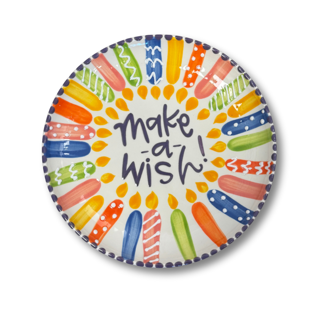 Colorful candles on a plate with 'make a wish!' text on a white background